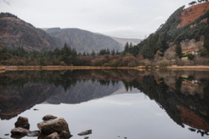 A tranquil lake nestled between mountain ridges in Wicklow, reflecting the sky and surrounding greenery.