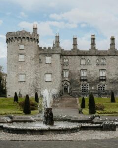 Kilkenny Castle with a central fountain in the foreground.