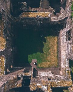 Aerial view of ancient abbey ruins surrounded by green fields in Ireland