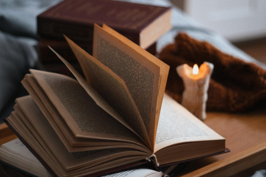 An open book resting beside a candle on a wooden table