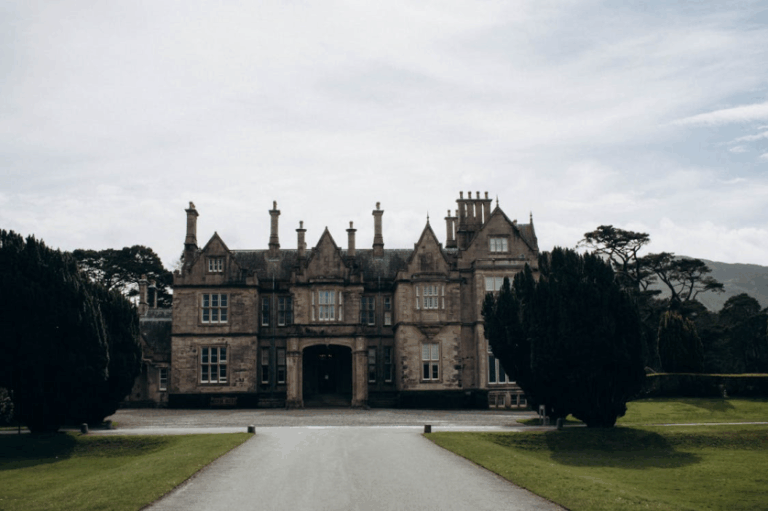Historic Irish manor house with long driveway and symmetrical architecture surrounded by trees
