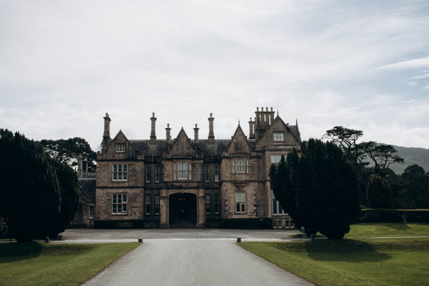 Historic Irish manor house with long driveway and symmetrical architecture surrounded by trees