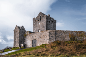 Stone fortified tower house on grassy hill near coastline in Ireland