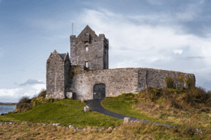 Stone tower house near coast with fortified walls and pathway leading to entrance
