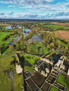 Aerial view of ancient monastic ruins surrounded by rivers and lush Irish farmland