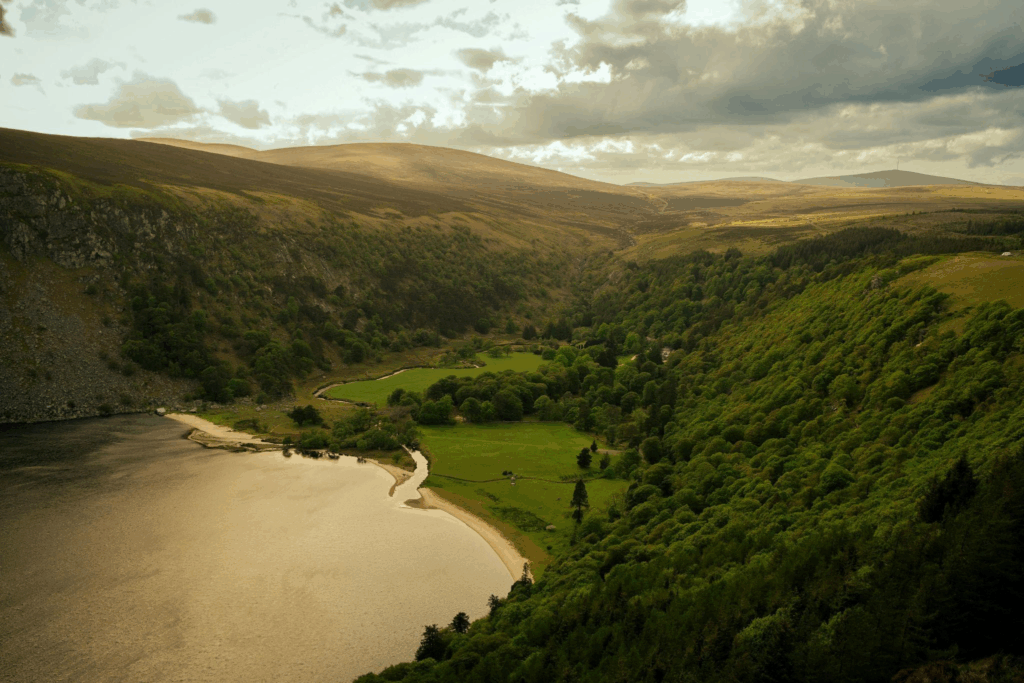 This photo shows a green grassy hill with a body of water in front of it.