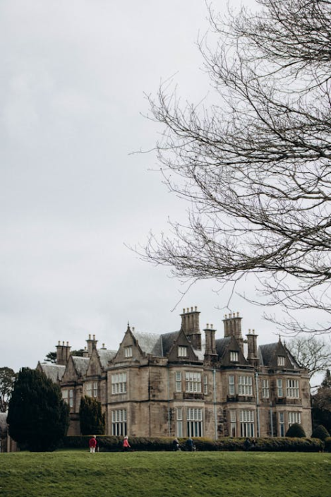 Historic Irish manor house surrounded by lawns and trees under overcast sky