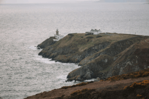 This photo shows a lighthouse at the edge of a cliff.