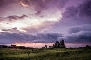 This photo shows a castle at sunset with grass around it.