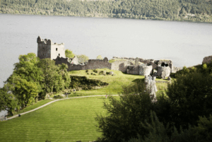 This photo shows the ruins of a castle by a lake.