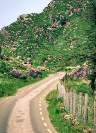 This image shows a winding road through green hills and rugged countryside.