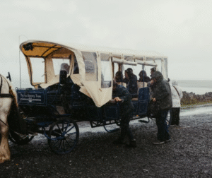 This image shows a horse-drawn carriage with passengers on a rainy day.
