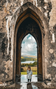 This image shows a child standing in an ancient stone archway.