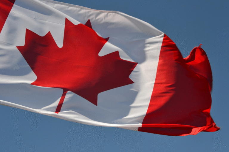 Canadian national flag waving against a clear blue sky.