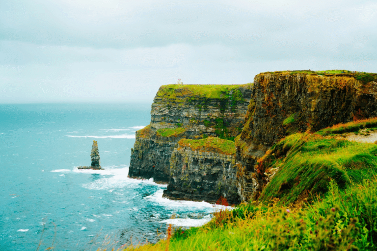 Dramatic ocean view from grassy coastal cliffs under an overcast autumn sky in Ireland.