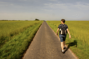 This photo shows a person walking along a quiet country road.