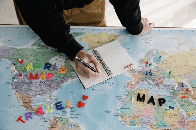 This photo shows a person writing in a notebook on a world map.