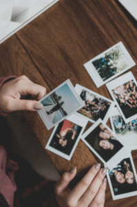 This photo shows hands arranging printed family photos on a table.